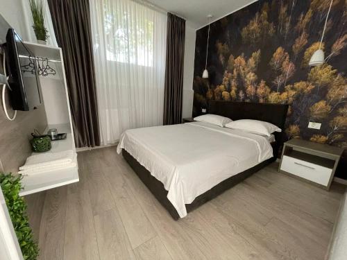 a bedroom with a bed with a painting on the wall at Pensiunea Prestige House in Curtea de Argeş