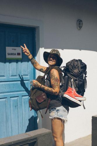 a woman with tattoos on her arm standing in front of a door at World Hostel - Canasvieiras in Florianópolis