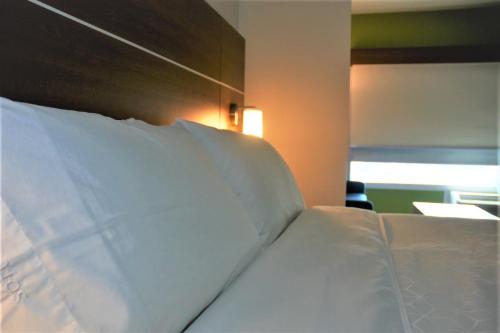 a bed with white sheets and a wooden head board at Holiday Inn Express & Suites - Edmonton SW – Windermere by IHG in Edmonton