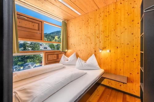 two beds in a room with a large window at Holzboxen Planneralm in Planneralm