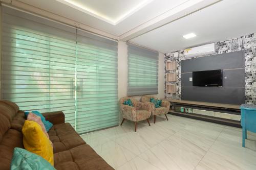 uma sala de estar com um sofá e uma televisão de ecrã plano em Sobrado Smart - Melhor Localização de Foz do Iguaçu em Foz do Iguaçu