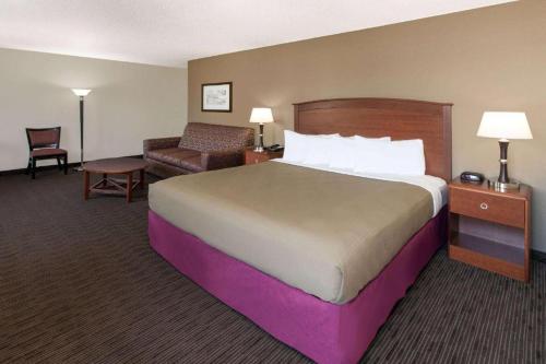 a hotel room with a large bed and a chair at AmericInn by Wyndham Grundy Center in Grundy Center