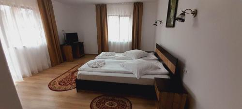 una camera da letto con letto, lenzuola e cuscini bianchi di Vila Maria Bran a Şimon