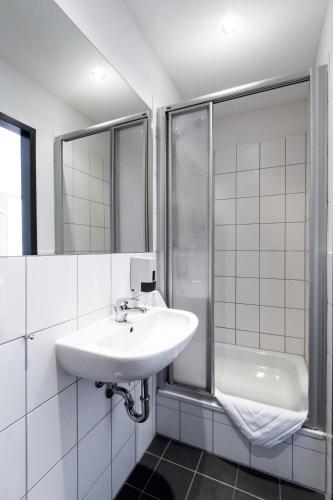 a white bathroom with a sink and a shower at Dream Inn Hotel Regensburg Ost in Regensburg