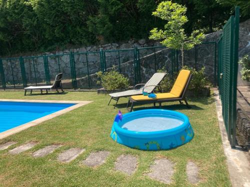 a backyard with a swimming pool and two chairs and a tub at Quinta de Varzielas - Agroturismo in Castelo de Paiva