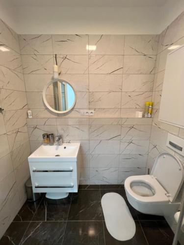 W łazience znajduje się toaleta, umywalka i lustro. w obiekcie The Dante Prague - Family Apartments with FREE PARKING w Pradze
