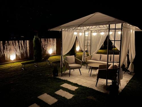 a gazebo with a couch and chairs under it at night at Pensiunea Prestige House in Curtea de Argeş