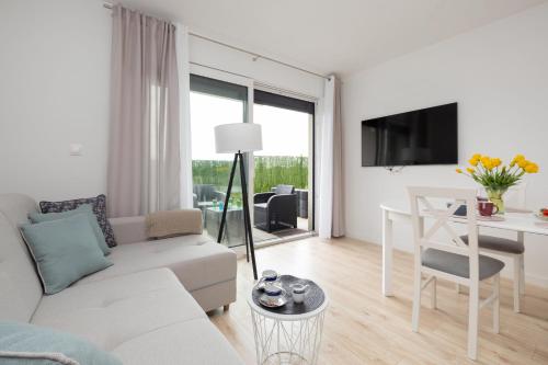 a white living room with a white couch and a table at Dwupoziomowy Apartament z Parkingiem - Taras i Balkon - 3 Sypialnie by Renters in Rewal
