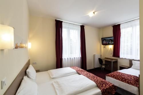 a hotel room with two beds and a desk at Dream Inn Hotel Regensburg Ost in Regensburg