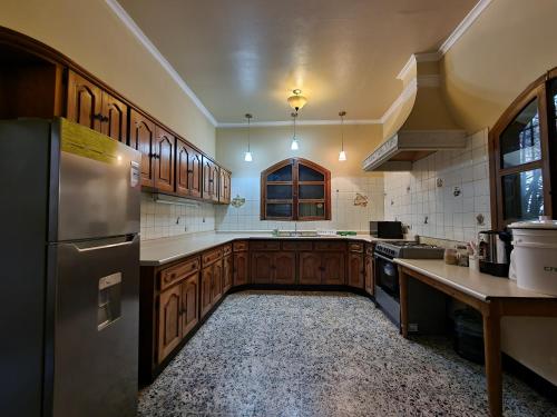 a kitchen with wooden cabinets and a stainless steel refrigerator at Central Hostel in Antigua Guatemala