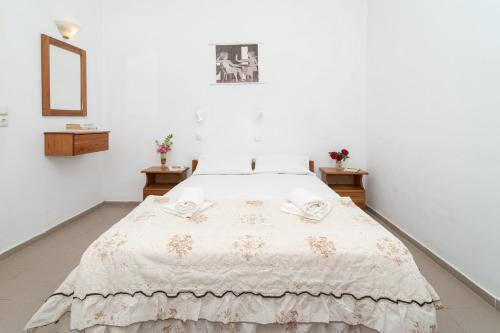 a bed in a white room with two tables at Ilias Apartments in Methoni