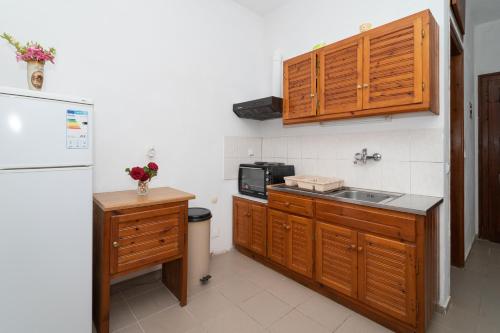 a kitchen with wooden cabinets and a sink and a refrigerator at Ilias Apartments in Methoni