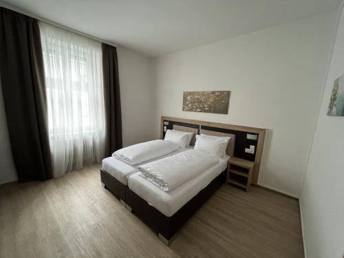 a bedroom with a bed with white sheets and pillows at City Hotel in Schopfheim