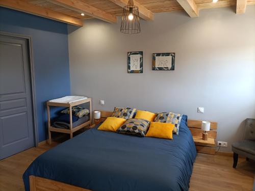 Un dormitorio con una cama azul con almohadas amarillas en La grenouille amoureuse, en Menat