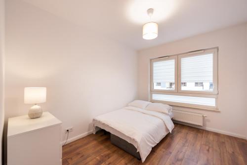 biała sypialnia z łóżkiem i oknem w obiekcie Saska Kępa Bright Apartament w Warszawie