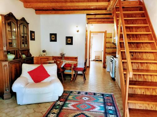 a living room with a white chair and a staircase at Green Riviera Case Vacanza in Borzonasca