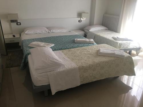 a room with three beds with white sheets at Stelmalu' in Novoli
