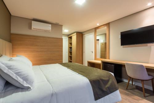a bedroom with a bed and a desk with a television at Laghetto Canela in Canela