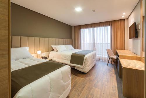 a hotel room with two beds and a desk at Laghetto Canela in Canela