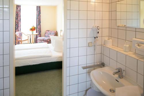 ein Bad mit einem Waschbecken und ein Bett in einem Zimmer in der Unterkunft Apart Hotel Weimar in Weimar