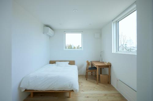 a white bedroom with a bed and a desk at Nippou no Ie Kamishihoro - Vacation STAY 58936v in Kami-shihoro
