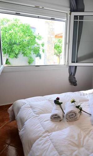a white bed with two towels and a window at Happinies apartments 1 in Soúrpi