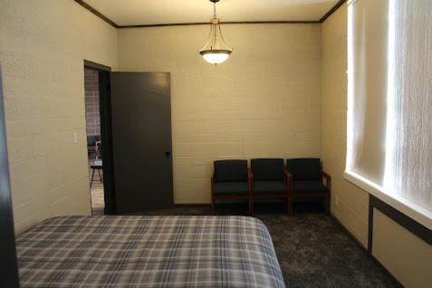 a room with a bed and two chairs in it at The Gathering Place in Salina