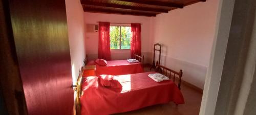 two beds in a room with red curtains at Cabaña Aguara in Colonia Carlos Pellegrini