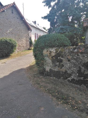 a stone wall next to a house and a street at Le Cerisier in Saint-Symphorien-de-Marmagne
