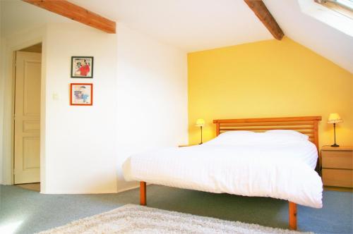 a bedroom with a white bed with a yellow wall at Le Cerisier in Saint-Symphorien-de-Marmagne