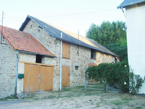an old stone building with two wooden garage doors at Le Cerisier in Saint-Symphorien-de-Marmagne