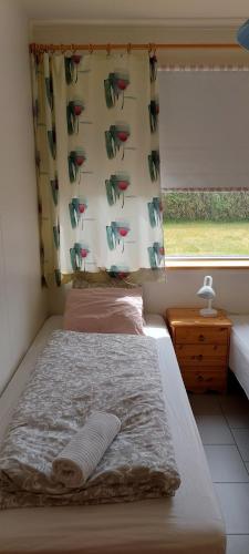 um quarto com uma cama e uma janela com uma cortina em Ægisholt privete house with hot tub em Patreksfjörður