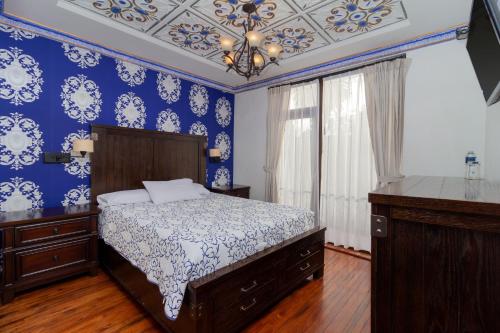 a bedroom with blue walls and a bed and a chandelier at Hotel Azul de la Plaza by Chat Noir in Cuenca