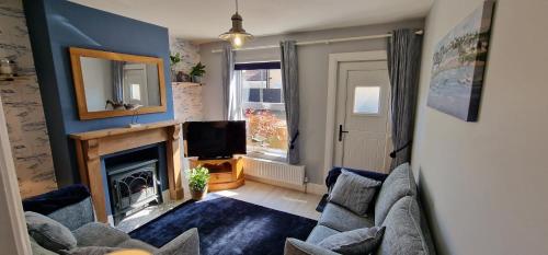ein Wohnzimmer mit Kamin und Fernseher in der Unterkunft Curlew Cottage - Suffolk Coastal Escapes in Pakefield