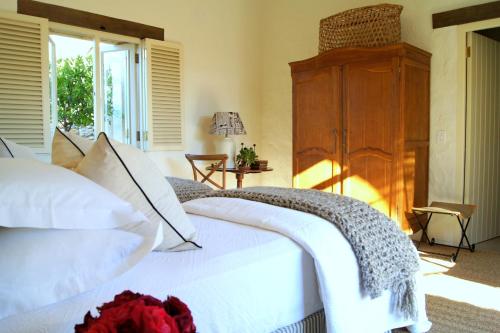 Un dormitorio con una cama blanca con una rosa roja. en The Cottage @ Montpellier en Franschhoek