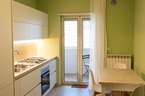 una cucina con pareti verdi, tavolo e lavandino di Casa Dominga a Monopoli