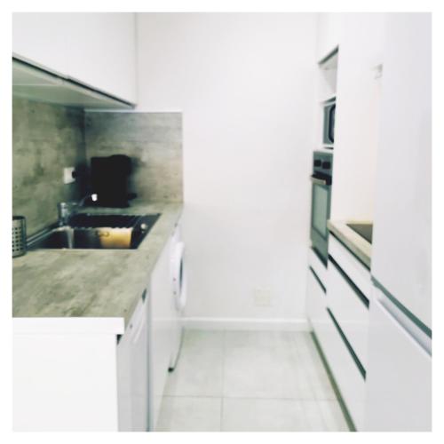 une cuisine blanche avec un évier et une cuisinière dans l'établissement COTE PLAGE HYPER CENTRE - Bord de mer, au Grau-du-Roi