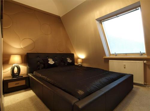 a bedroom with a large black bed with a window at Apartament przy Krupówkach in Zakopane