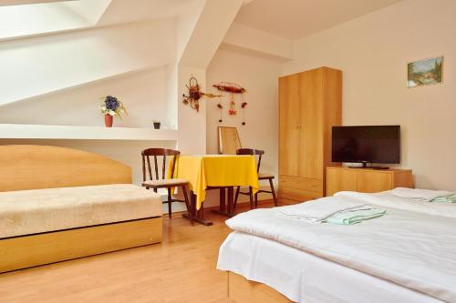 a bedroom with two beds and a table and a television at Penzión a Reštaurácia u Jeleňa in Stará Ľubovňa