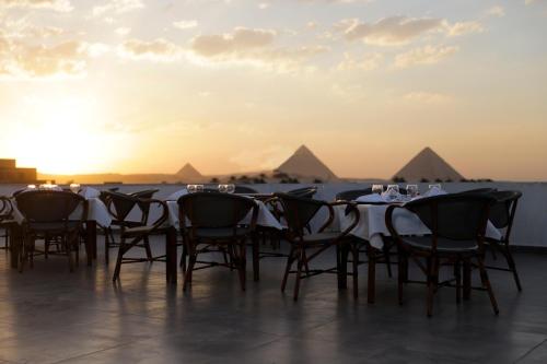 a table and chairs with the pyramids in the background at Pyramids Oasis Hotel in Cairo