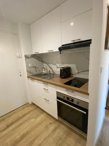 La cuisine est équipée de placards blancs et d'un four avec plaques de cuisson noires. dans l'établissement Studio Saint cyprien Plage, à Saint-Cyprien
