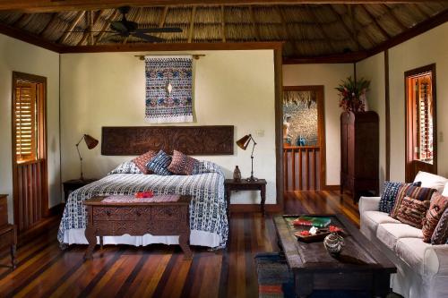 a bedroom with a bed and a couch at Blancaneaux Lodge by Francis Ford Coppola in San Ignacio