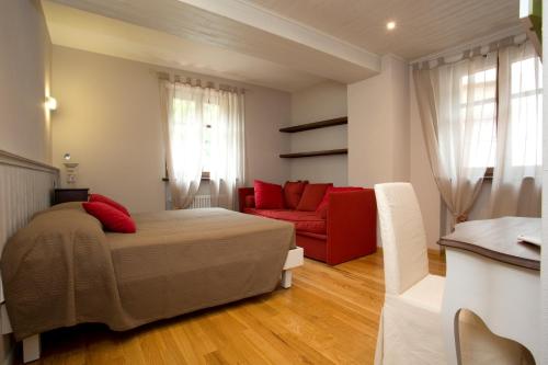 a bedroom with a bed and a red couch at B&B La Ceramica Moline in Vicoforte