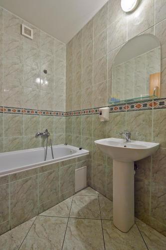 a bathroom with a sink and a tub and a mirror at Penzión a Reštaurácia u Jeleňa in Stará Ľubovňa