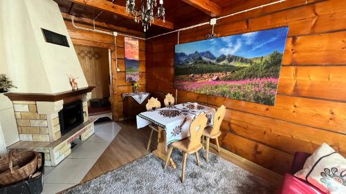 a dining room with a table and a large painting on the wall at Domek Pod Kogutkiem Na Dolinie in Bukowina Tatrzańska