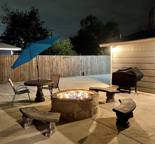 a patio with a fire pit and a table and an umbrella at Cozy Haus Relaxing 'Home Base' WiFi Location Close to Town and Rivers, Schlitterbahn, Gruene in New Braunfels