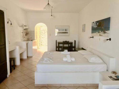 a white bedroom with a bed and a bathroom at Agios Pavlos Studios in Aegiali