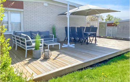 a wooden deck with chairs and an umbrella at Nice Home In Alnö With Kitchen in Sundsbruk