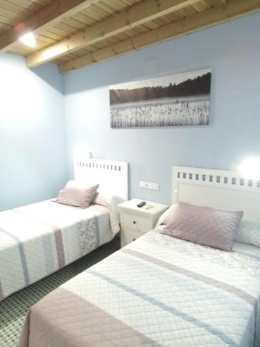 a bedroom with two beds and a painting on the wall at Casa Rural La Plata in Aljucén