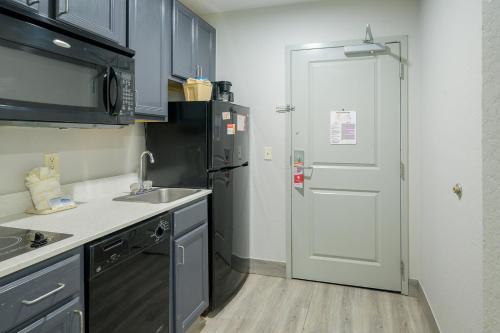 a kitchen with a refrigerator and a sink and a door at Hawthorn Extended Stay by Wyndham Panama City Beach in Panama City Beach